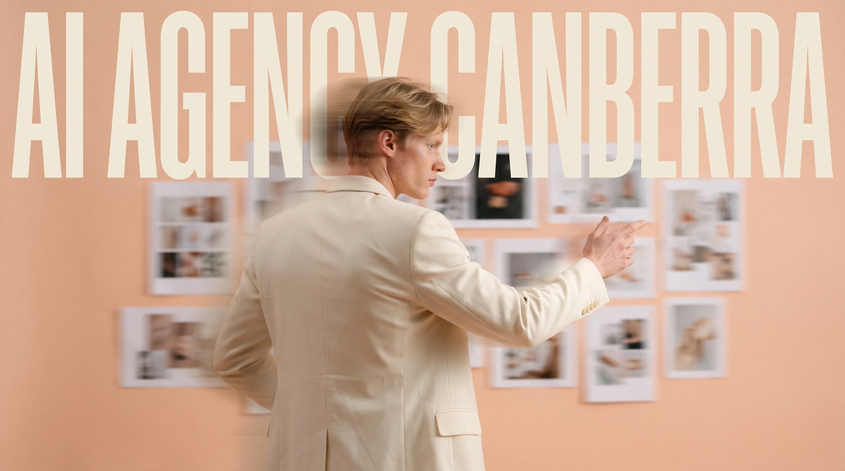Person mid-turn in a peach-backdrop studio, three-quarter framing, gesturing toward a wall of unbranded mood-board prints, wearing a tailored cream