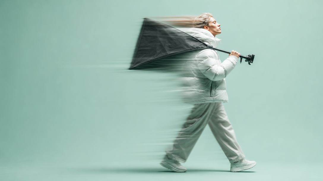 A person mid-step across a mint studio floor carrying an unbranded softbox arm over one shoulder, shot in profile with negative space to the left