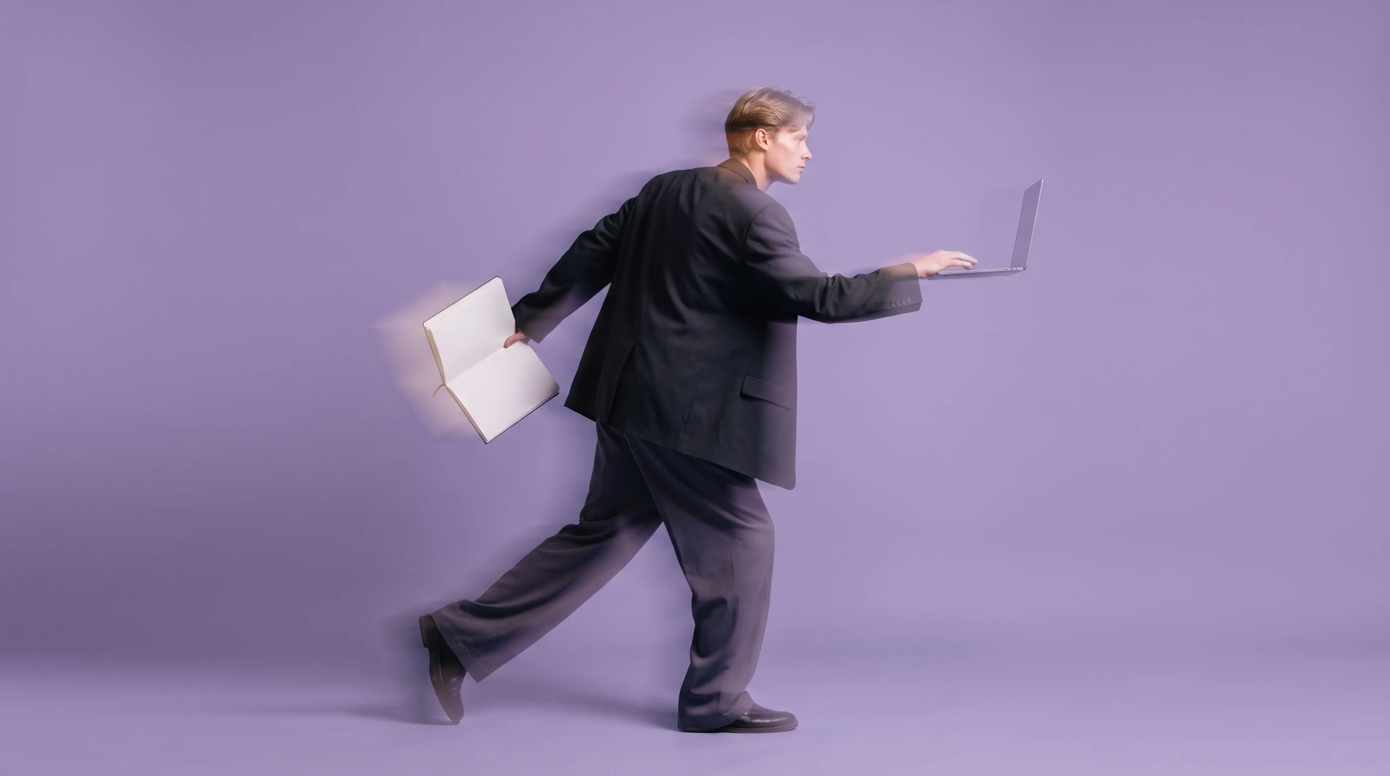 A person mid-step in a lilac-backdrop studio, holding an open sketchbook and reaching toward an unseen screen, shot in profile with loose
