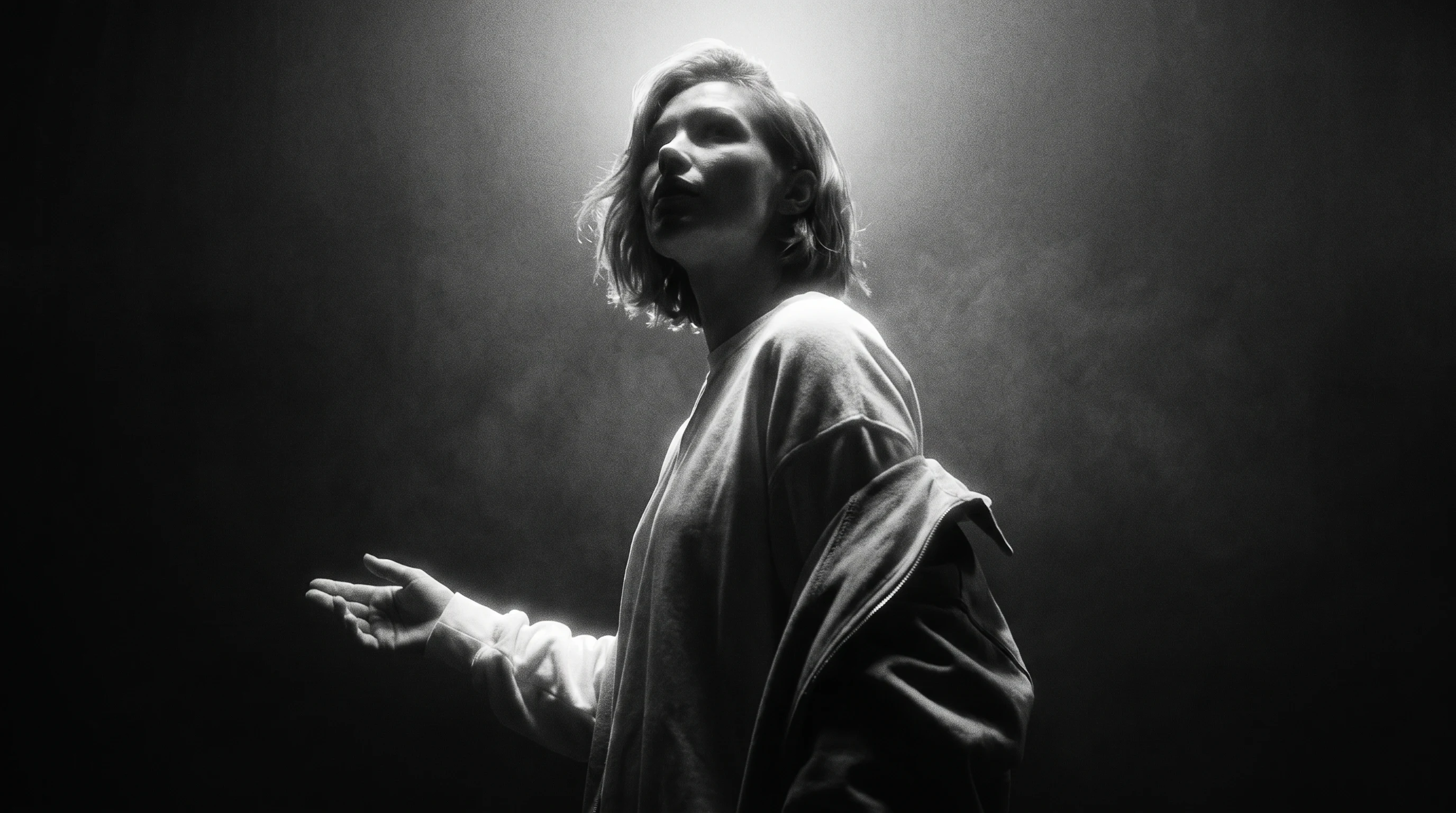 A creative director mid-turn in an editing suite, gesturing at an unbranded monitor showing storyboard frames, jacket draped over one shoulder