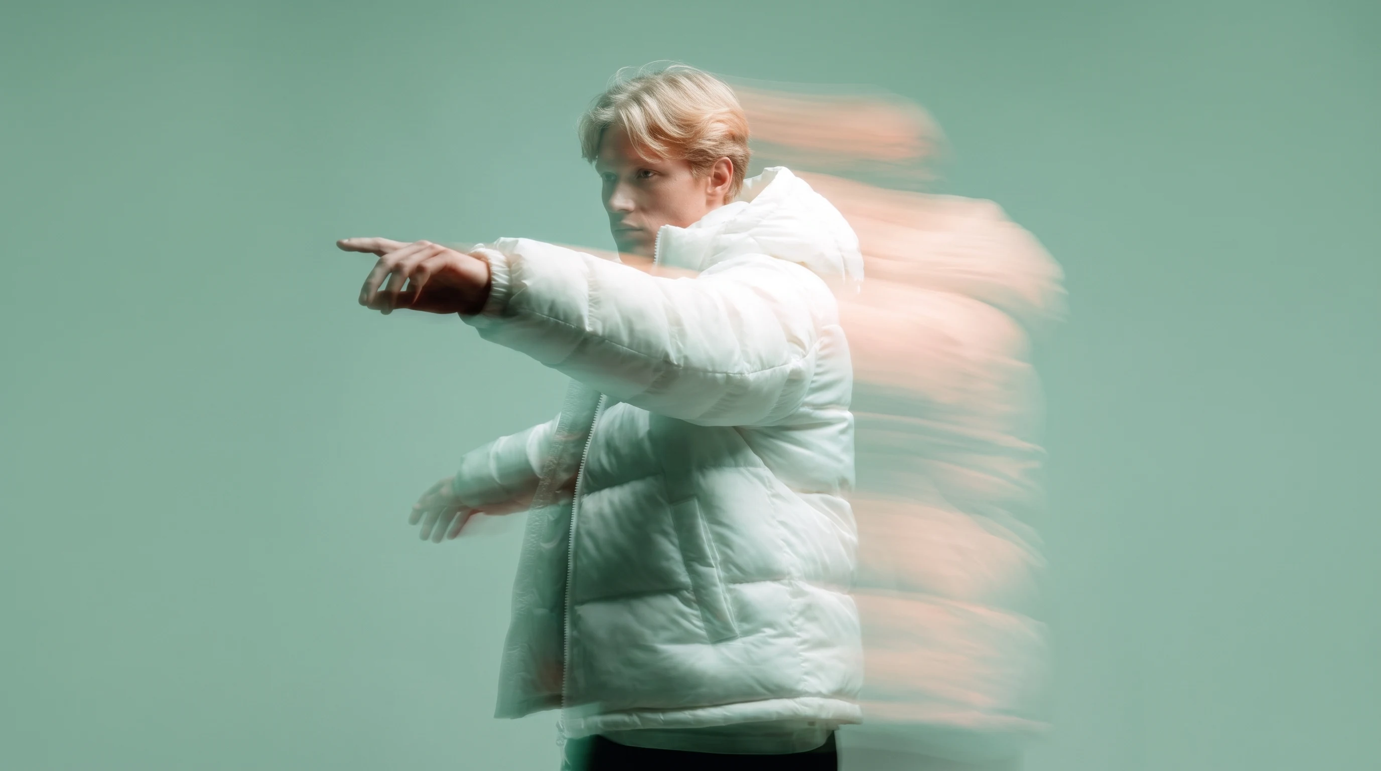 A designer mid-spin in a mint studio, one arm extended gesturing toward an invisible canvas, loose creative-director energy, three-quarter framing
