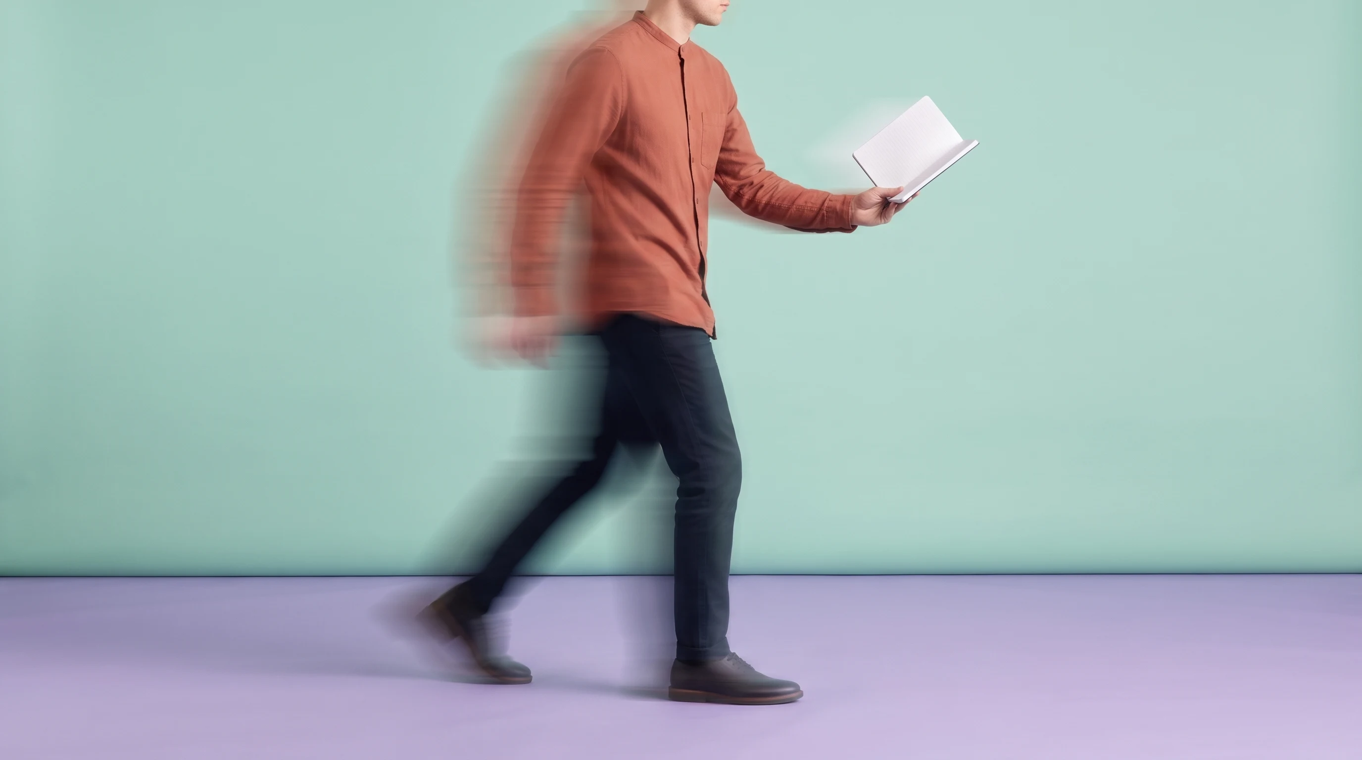 A person mid-step across a lilac studio floor, holding a slim notebook open at arm's length, wearing a terracotta collarless shirt and dark trousers,